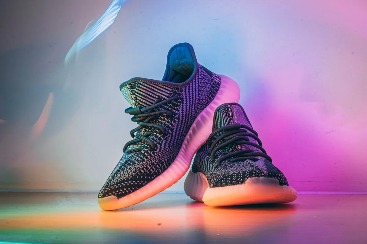 A pair of knit running shoes lit by a colourful gradient
