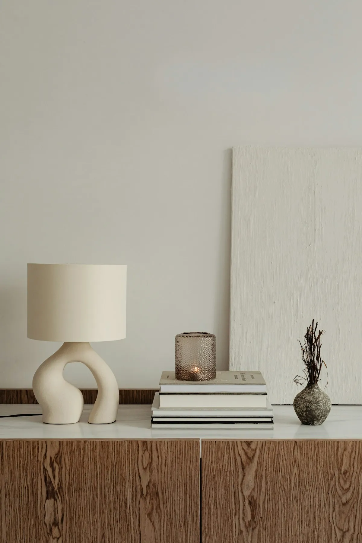 A sculptural ceramic lamp beside a stack of books